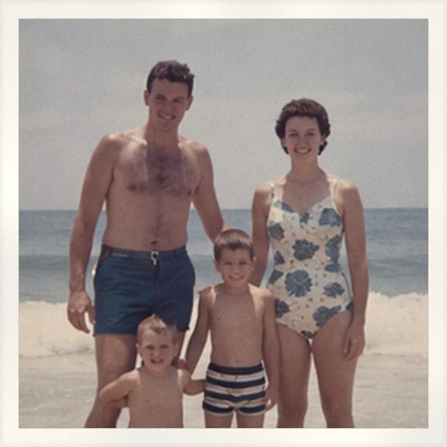 A family of four standing at the edge of the surf, with no date printed anywhere on the photo.