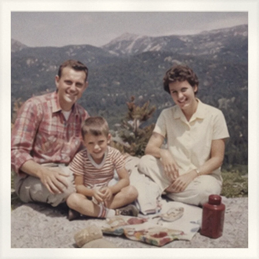 Two parents and a young boy on a picnic blanket in the mountains, with no date printed anywhere on the photo.