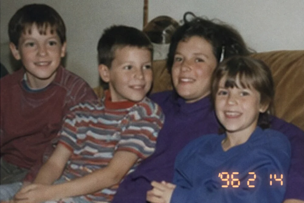 Four children on a sofa, with an orange camera date stamp reading 96 2 14 in the corner of the print.