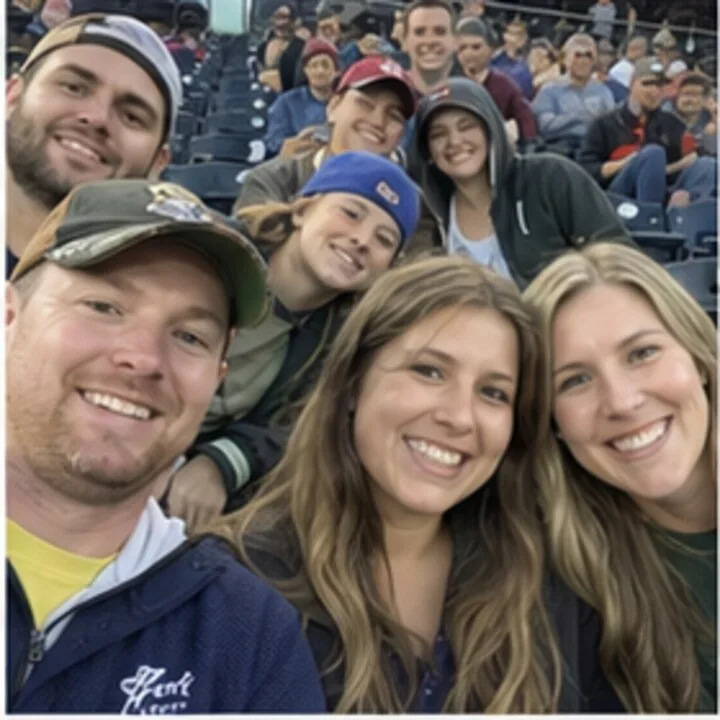Six young adults leaning in for a selfie in stadium seats
