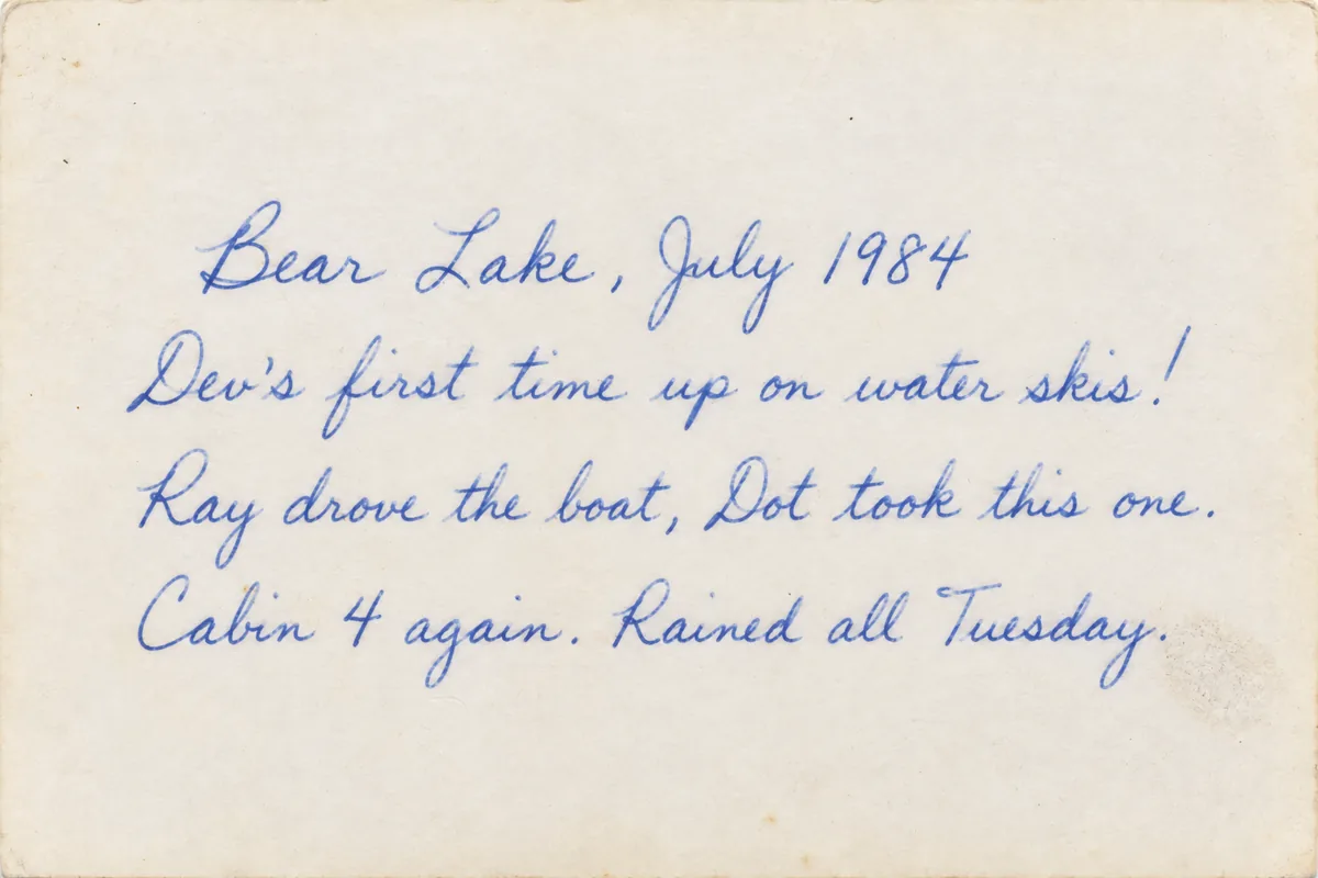 The back of a 1984 print, four lines in blue cursive: Bear Lake, July 1984. Dev's first time up on water skis! Ray drove the boat, Dot took this one. Cabin 4 again. Rained all Tuesday.