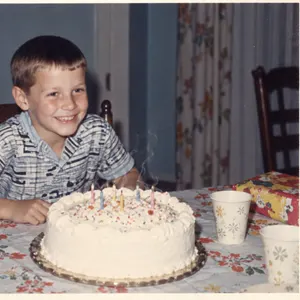 A framed 1968 print of a boy behind his birthday cake