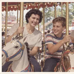 A 1974 print of a mother and son riding carousel horses