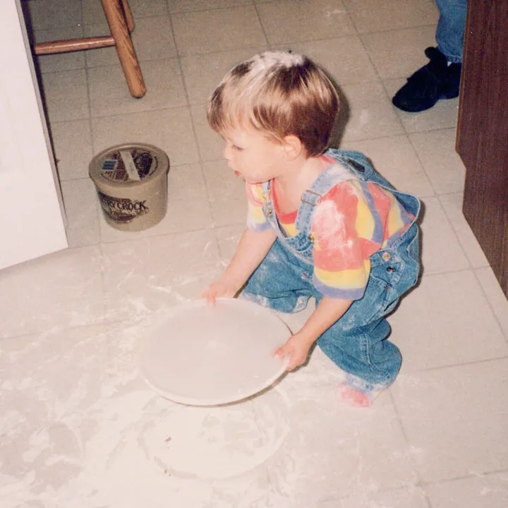 A toddler playing in spilled flour