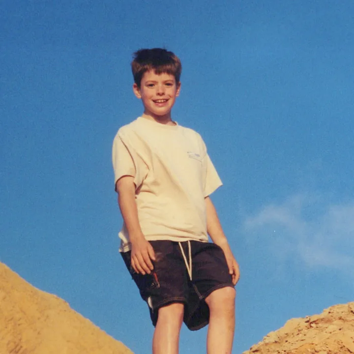 A boy standing on sandstone under a blue sky