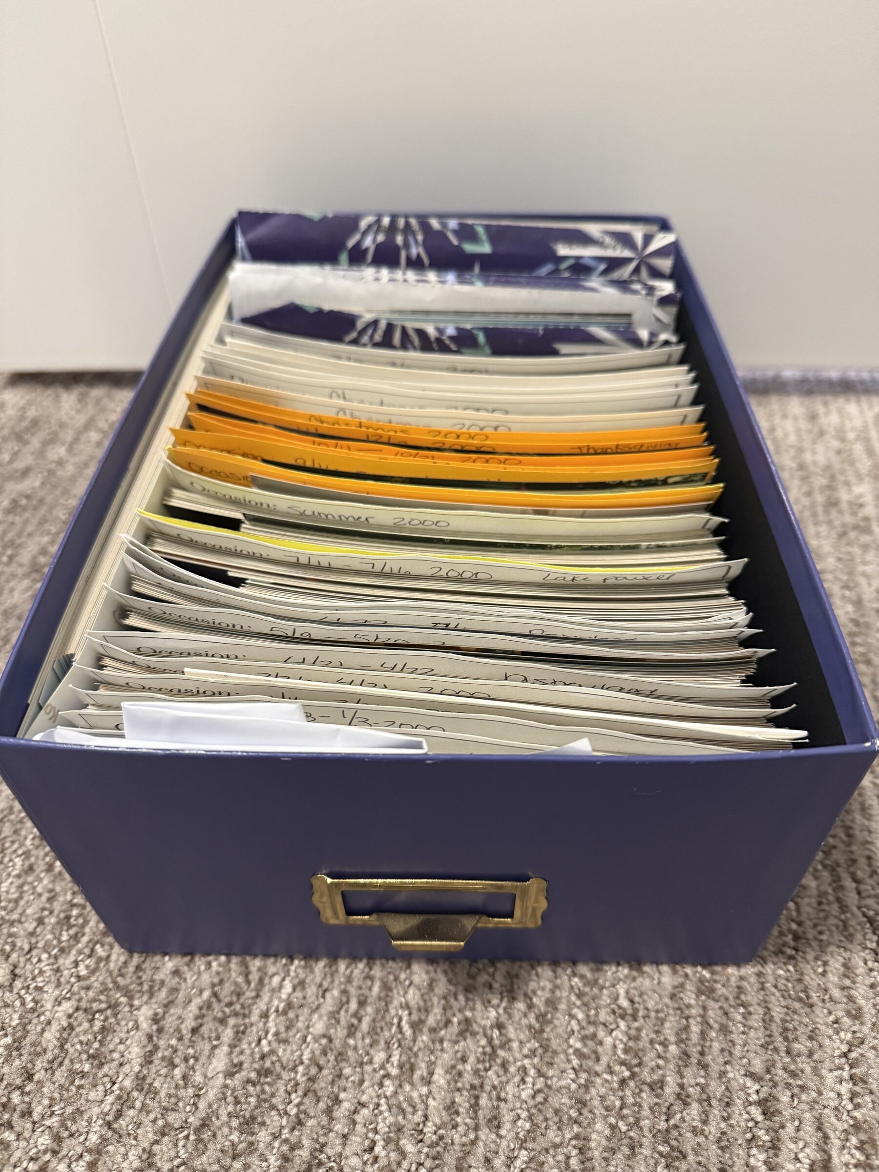A storage box filled with envelopes of loose printed family photos.